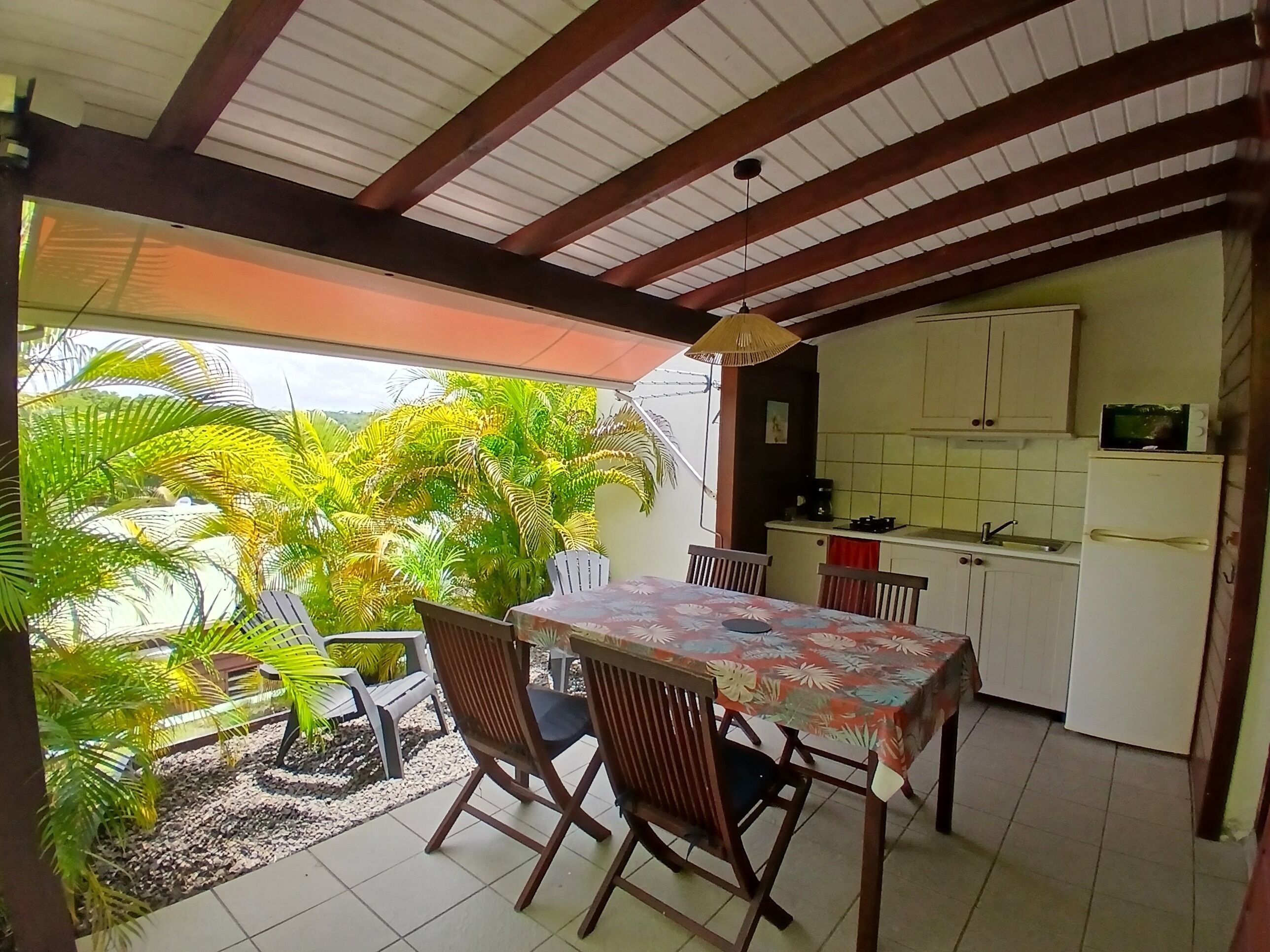 Un comedor con mesa y sillas, una cocina con muebles y electrodomésticos, y vistas a zonas verdes al exterior.