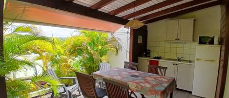 Un comedor con mesa y sillas, una cocina con muebles y electrodomésticos, y vistas a zonas verdes al exterior.