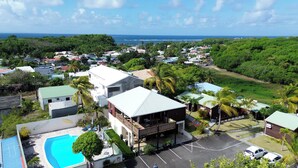 A residential area with a large house featuring a balcony, a swimming pool, and a view of the ocean. - Residence Ti Village Créole (Sainte-Anne)