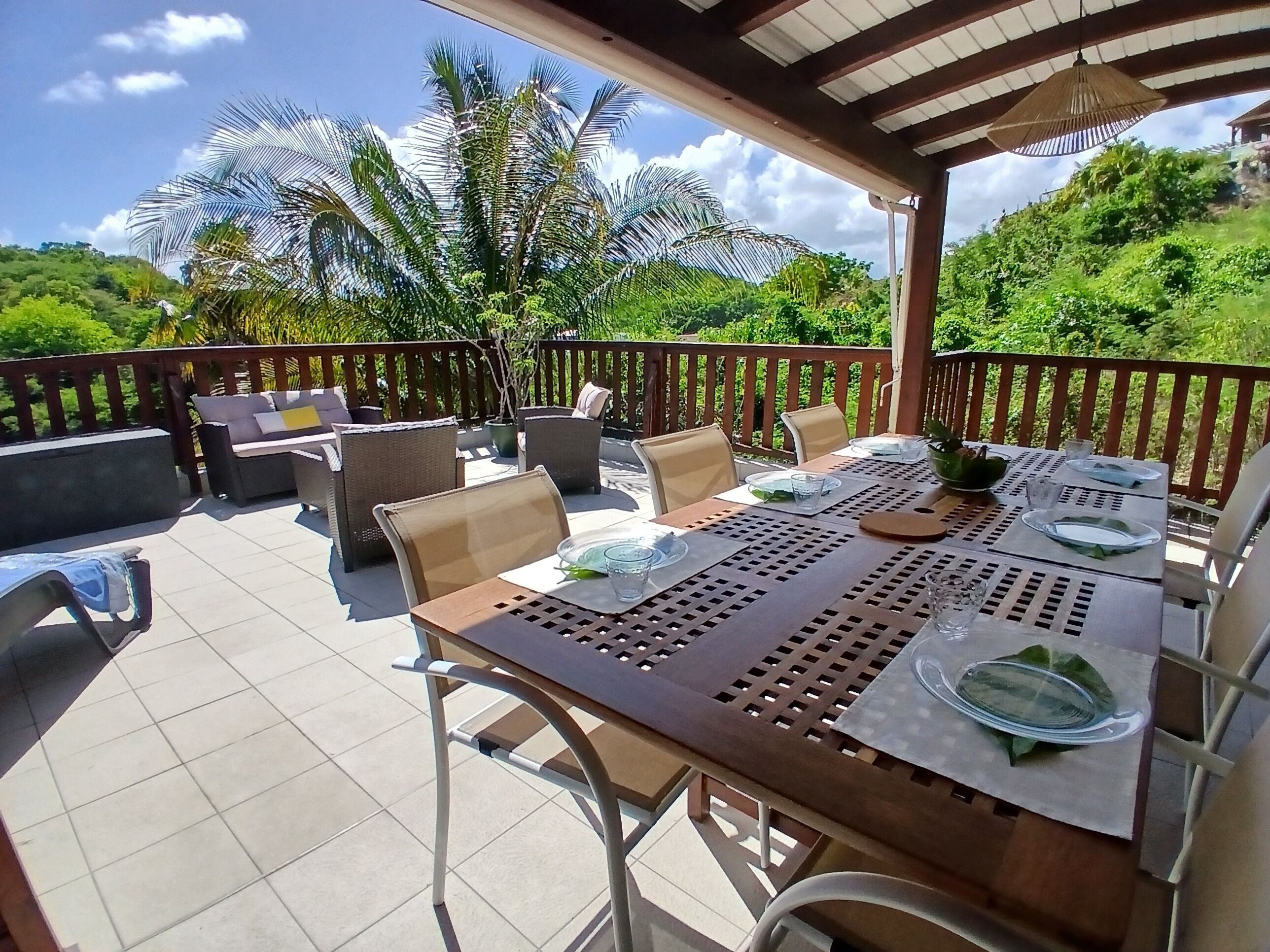 Eine Terrassengaststätte mit Esstisch, umgeben von Stühlen und einem hölzernen Geländer.