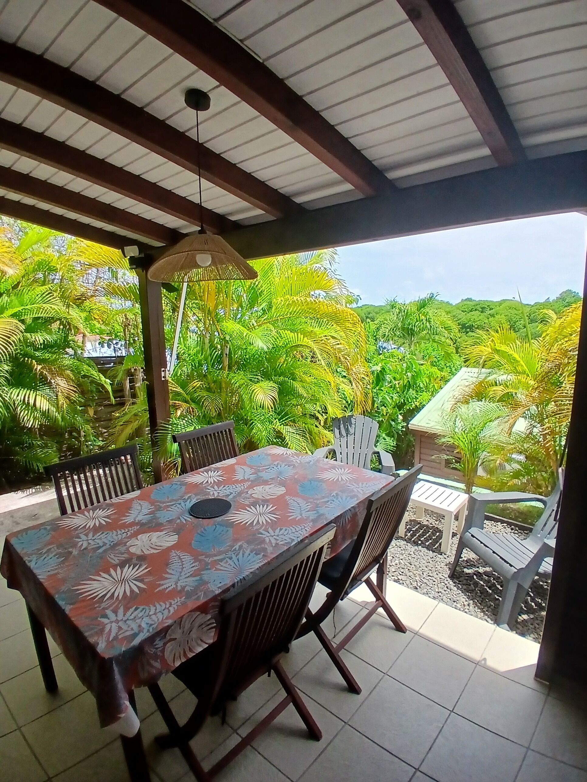 An outdoor patio with a table and chairs, surrounded by lush greenery and a view of the landscape.