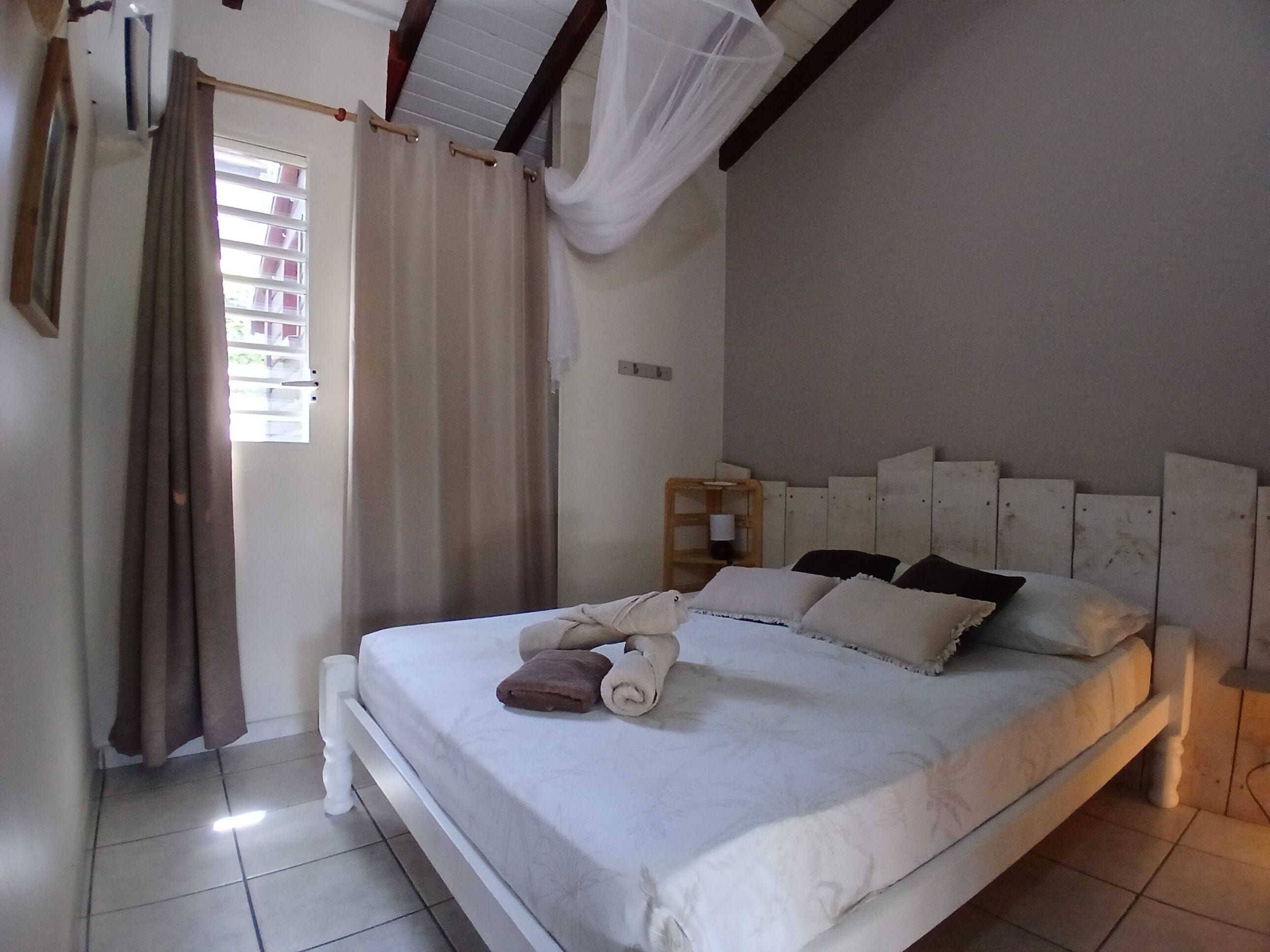 Une chambre à coucher avec un lit, des rideaux, une table de chevet et une tête de lit.