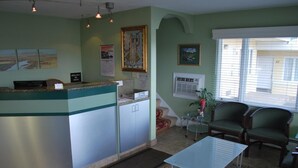 A reception area with a counter, cabinets, a small table, and two chairs. - Plaza Inn Great Falls (Great Falls)