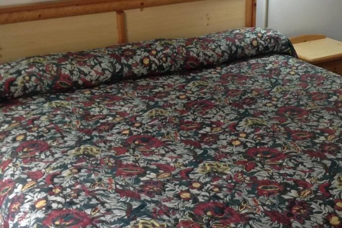 Een bed met een bloemenprint deken en een houten hoofdbord.