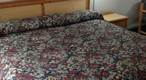 A bed with a floral bedspread and a wooden headboard. - Plaza Inn Great Falls (Great Falls)