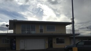 A two-story building with a flat roof, a garage door, and a parking lot. - Plaza Inn Great Falls (Great Falls)