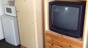 A compact room with a wooden cabinet, a microwave, and a television on a wooden stand. - Plaza Inn Great Falls (Great Falls)