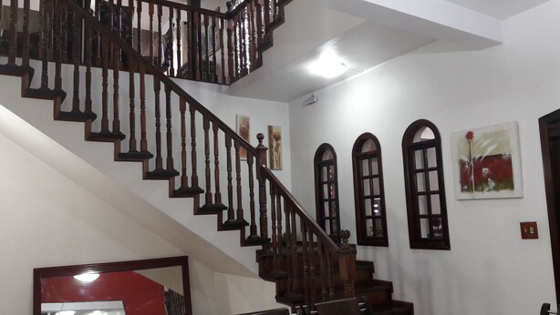 A staircase with wooden balusters and a handrail, leading to an upper floor. - Pousada Sognares (Guarulhos)