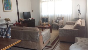 A living room with a sofa, armchairs, a coffee table, and a television. - Pousada Sognares (Guarulhos)