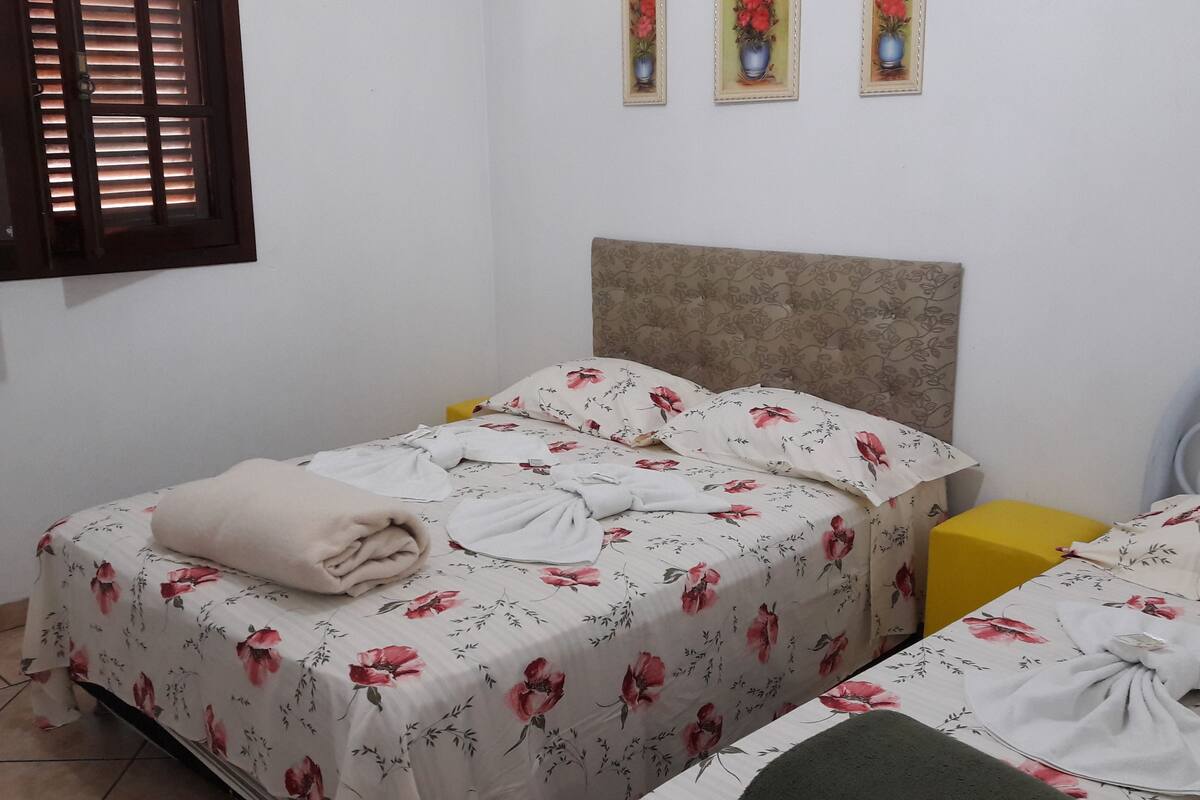 A bedroom with two beds, each with floral bedding and a headboard.