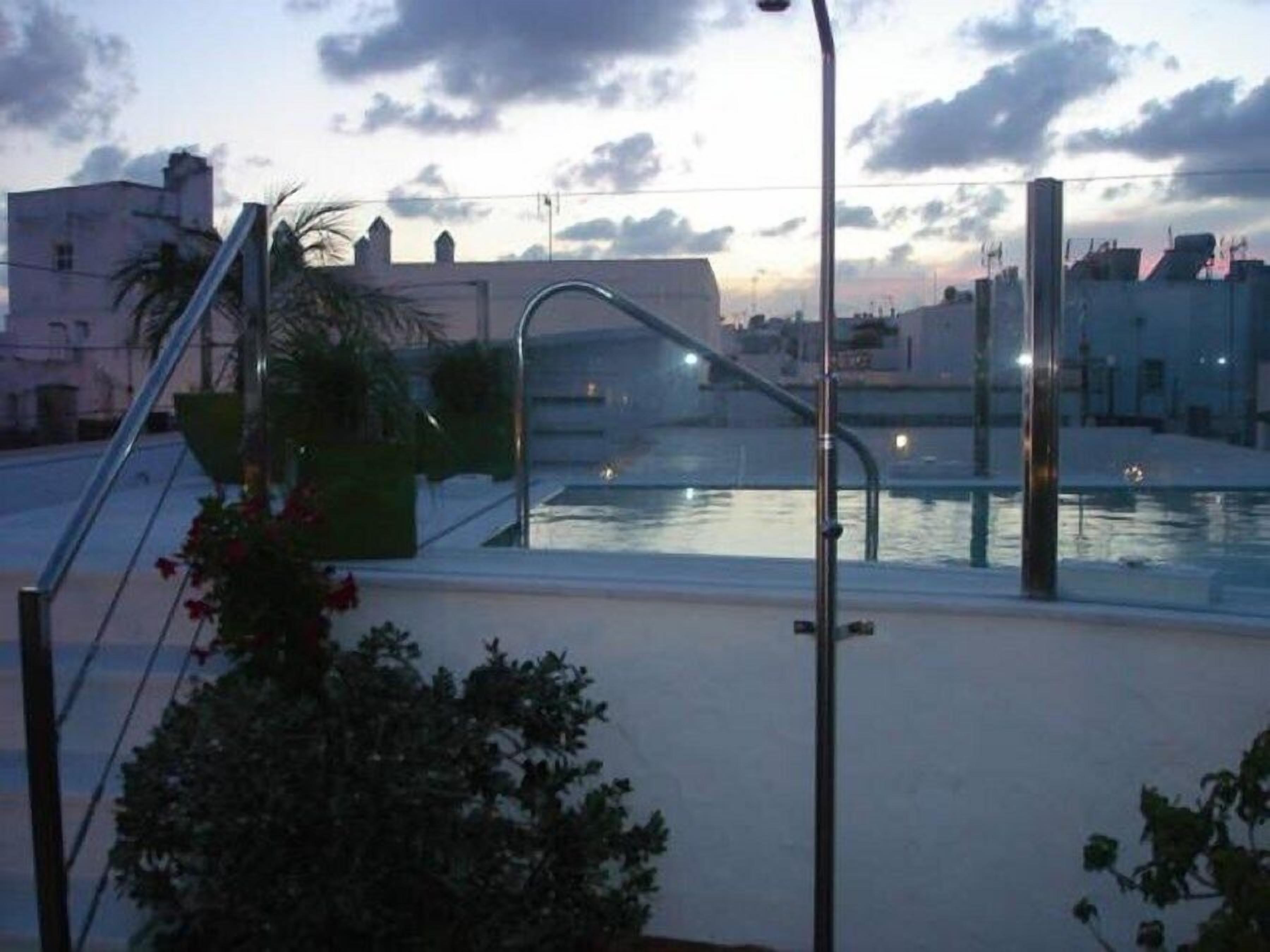 A rooftop pool with a metal railing and a staircase leading down.