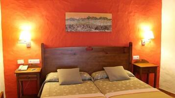 A double bed with two pillows, a wooden headboard, and two bedside tables with lamps.