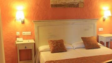 A bedroom with a bed, two bedside tables, a nightstand, a lamp, and a wall-mounted artwork.