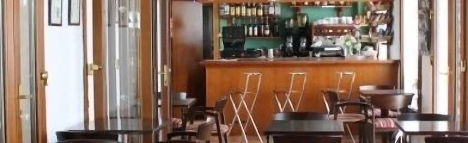 Una zona de bar con barra, taburetes y un área de estar con mesas y sillas.