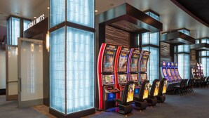 A row of slot machines in a modern gaming area with large windows and a "HIGH LIMITS" sign.