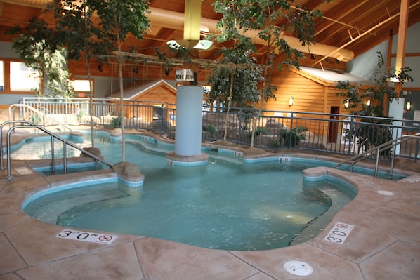 An indoor swimming pool with a 30-foot depth, surrounded by a wooden deck and metal railings. - Ho-Chunk Casino Hotel - Wisconsin Dells (Baraboo)
