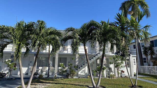 A building with multiple floors, palm trees, and a staircase. - Pelican By The Sea (Pompano Beach)