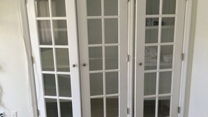 A set of three white doors with glass panels, each door has a handle and a lock. - Pelican By The Sea (Pompano Beach)