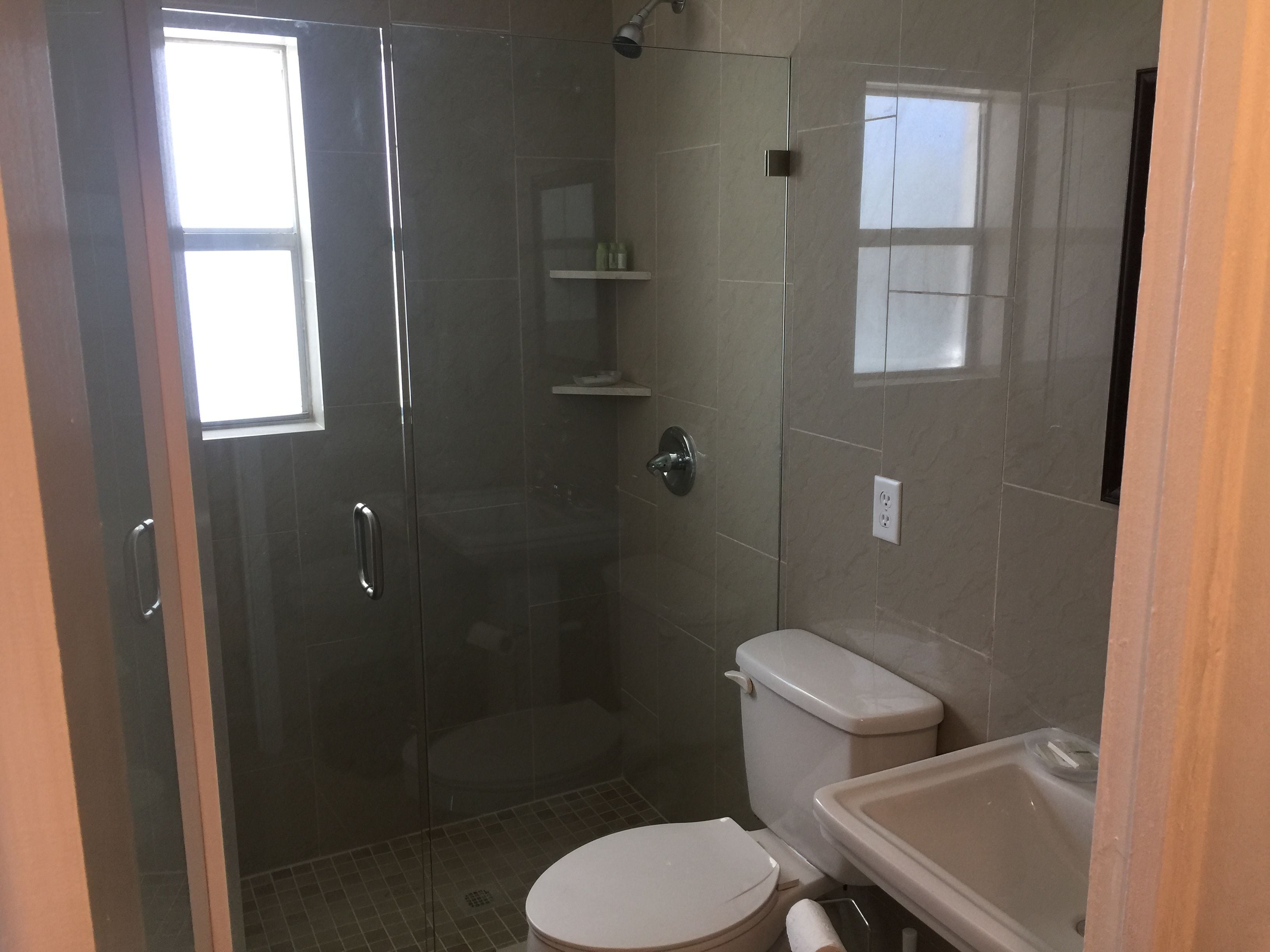 Une salle de bain avec une douche à parois de verre, des toilettes et un lavabo.