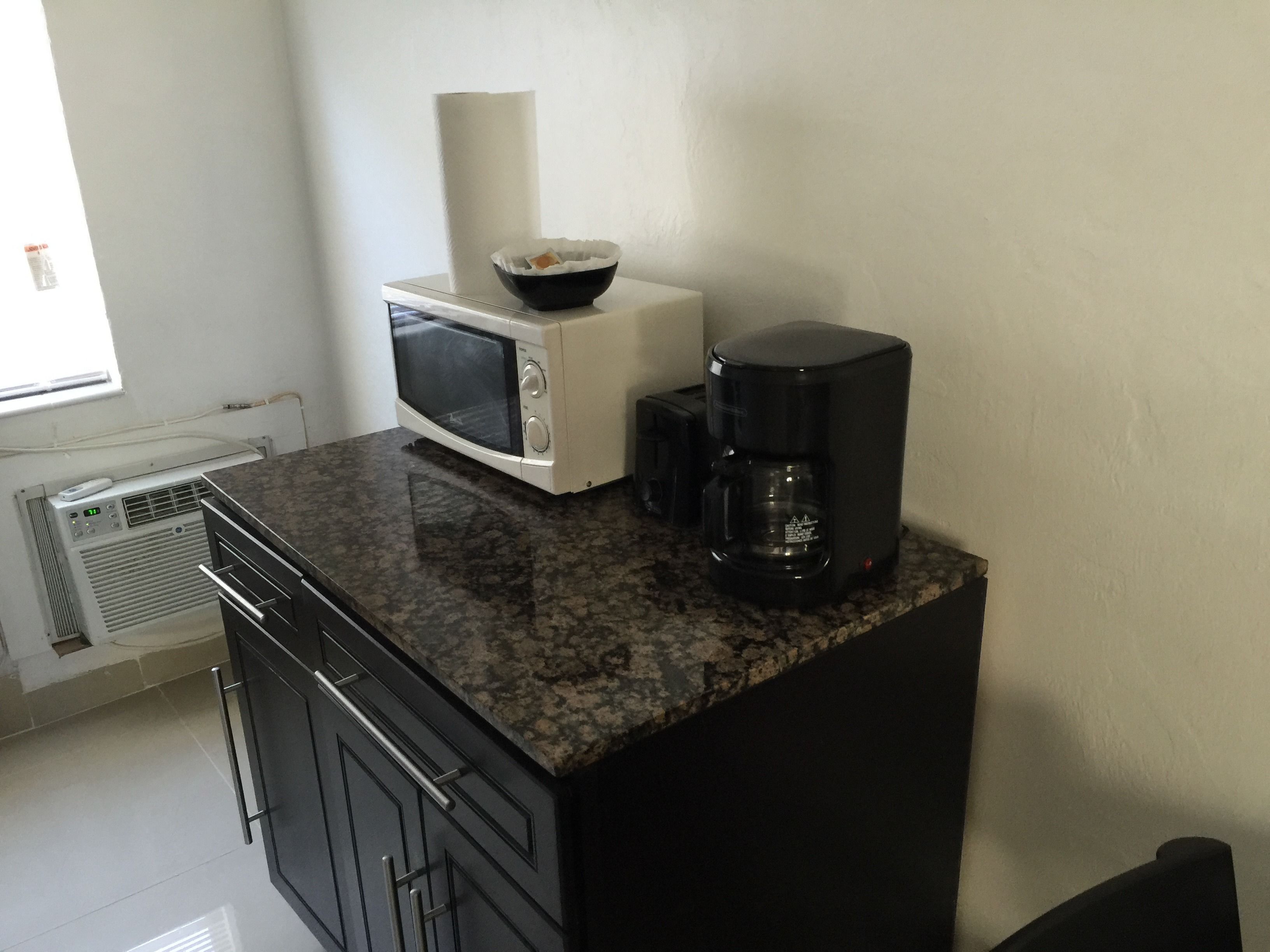 A kitchen with a microwave, coffee maker, and a bowl on the counter.