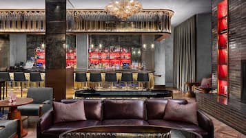 A bar area with seating, a bar counter, and a large chandelier.