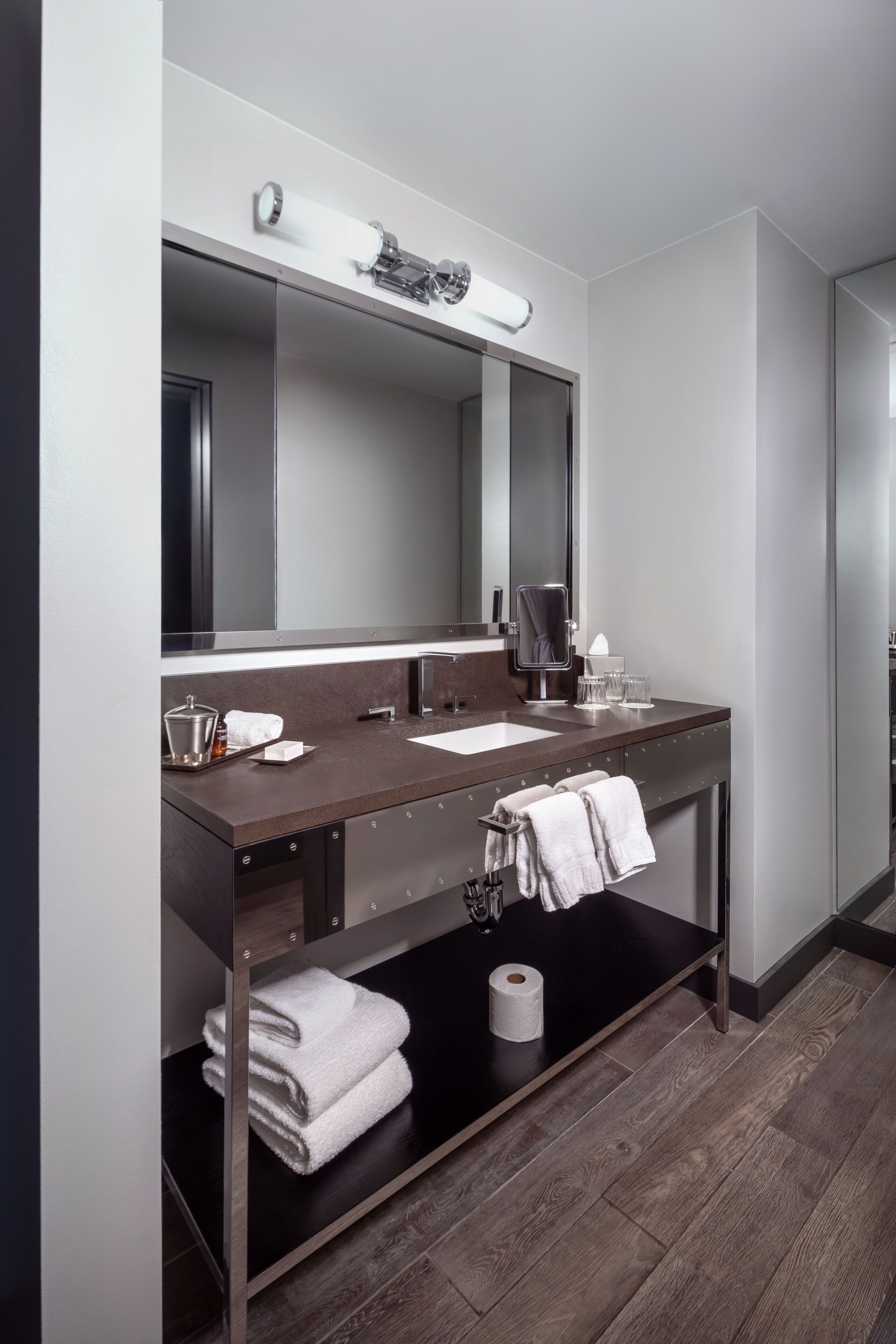 Een moderne badkamer met een donker houten wastafelmeubel, een grote spiegel en een inbouwwastafel.