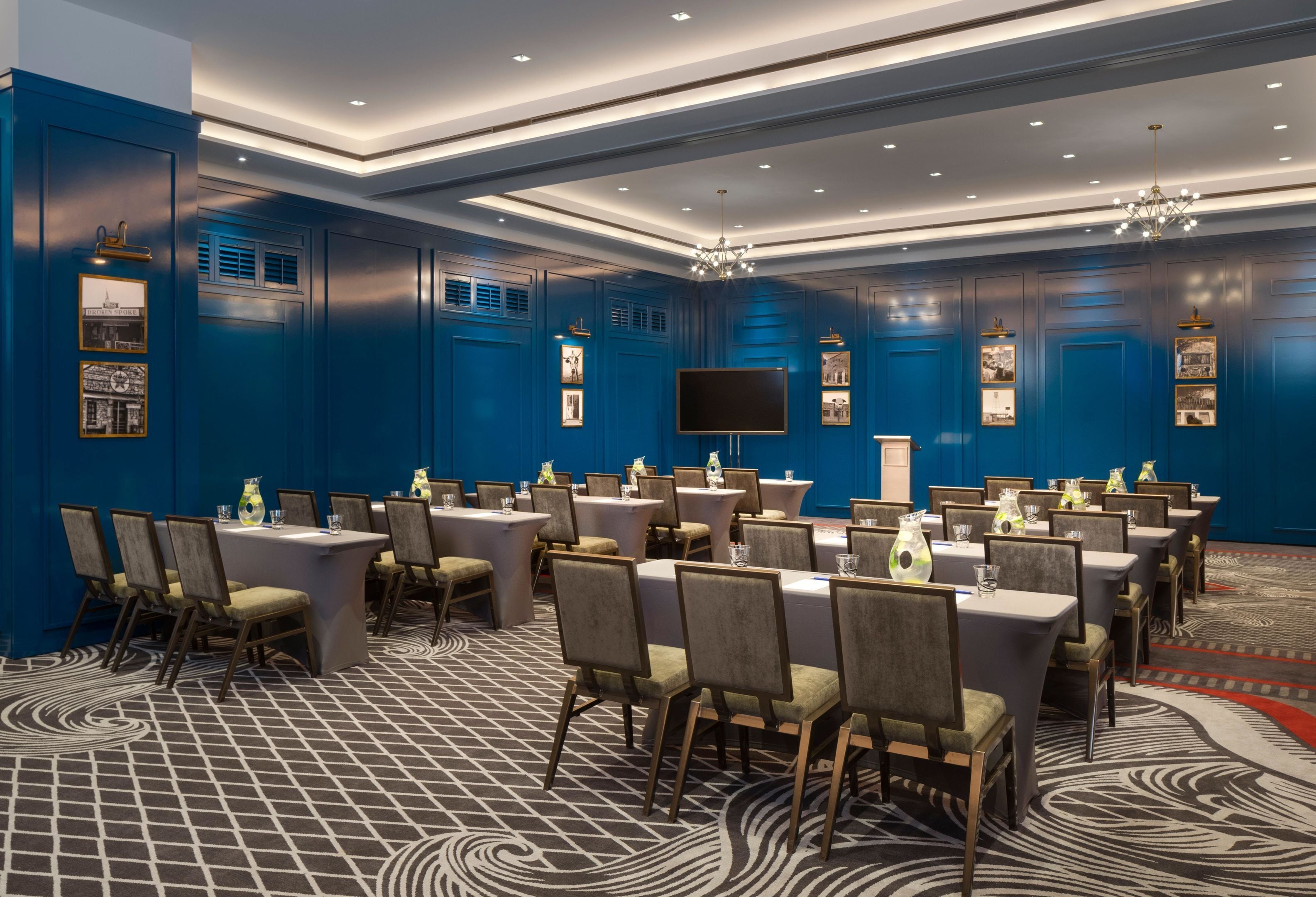 A conference room with tables and chairs, a flat-screen TV, and framed pictures on the walls.