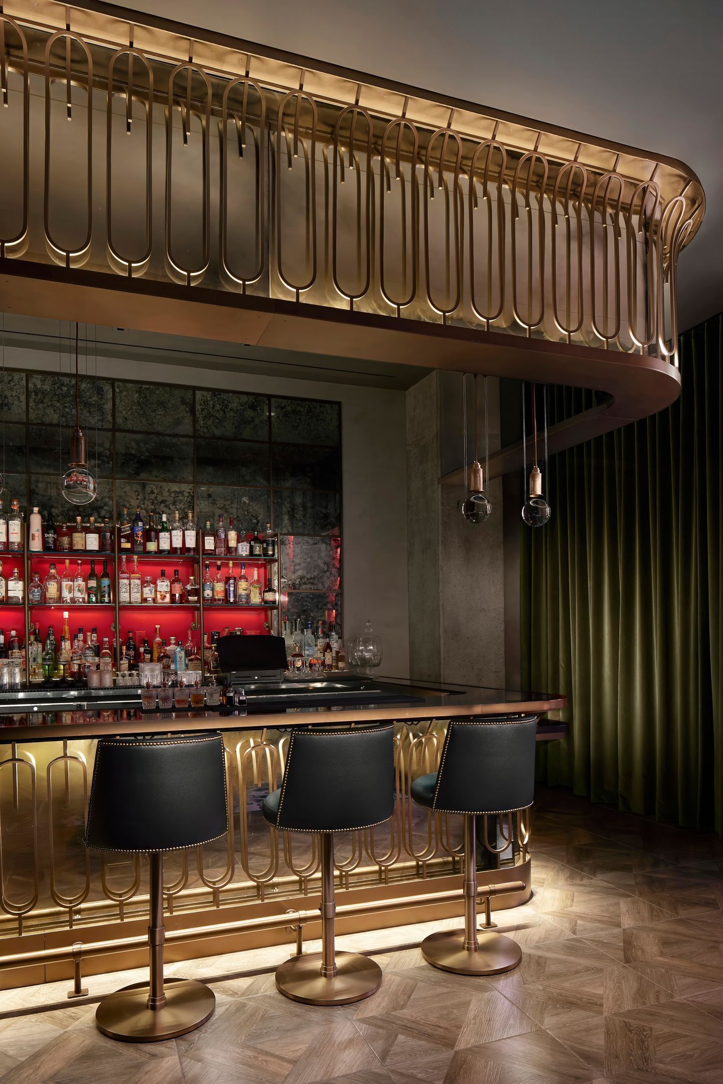 Zona de bar con diseño moderno, que incluye una barra, taburetes y una variedad de botellas.