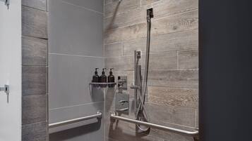 A modern shower with a wooden wall panel, a handheld showerhead, and a handheld faucet.