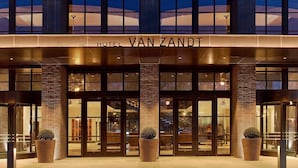 Exterior del Hotel Van Zandt, con un diseño moderno que destaca por amplias ventanas de vidrio y una entrada imponente.