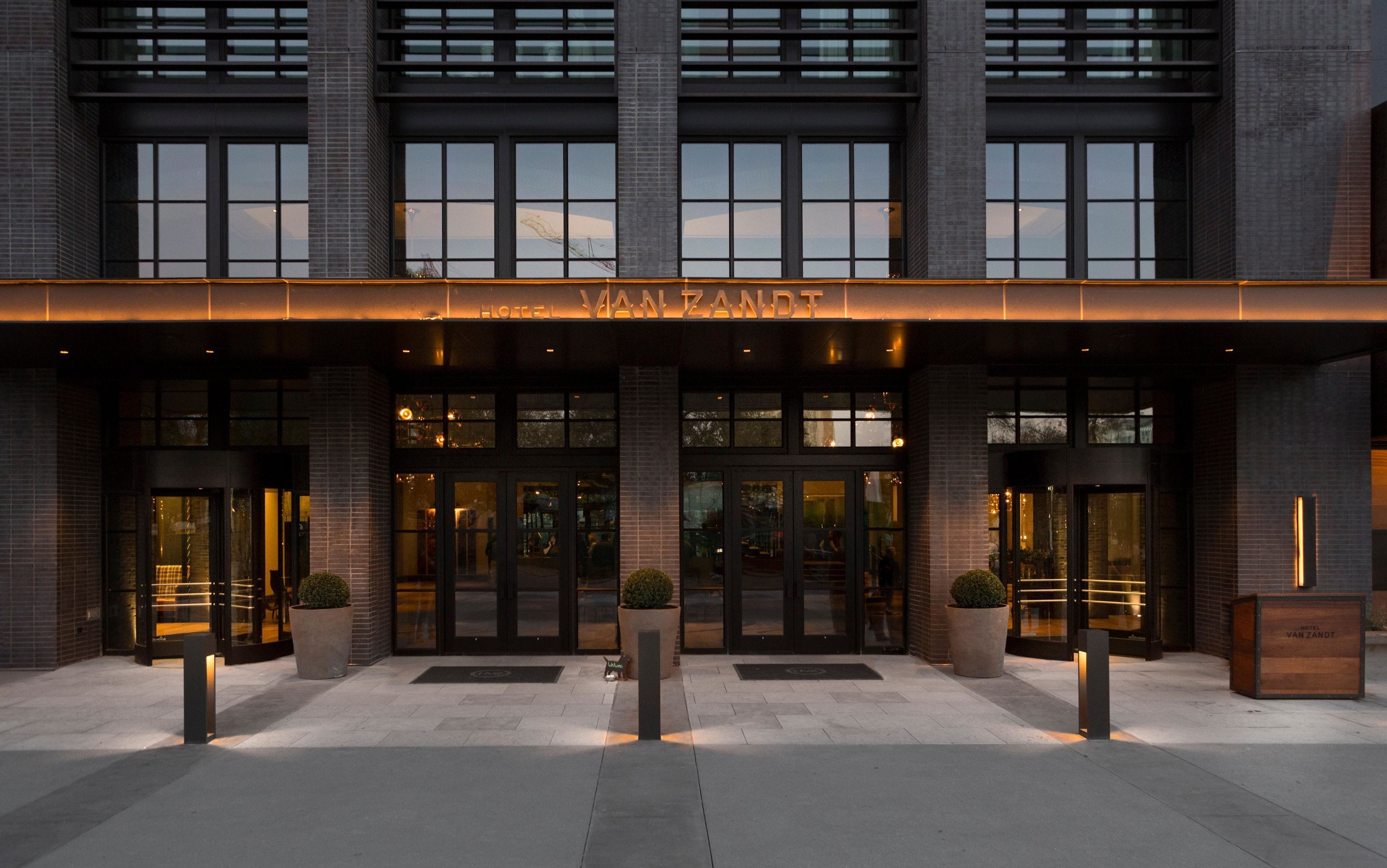 A hotel entrance with a modern facade, large glass doors, and a sign above the entrance.