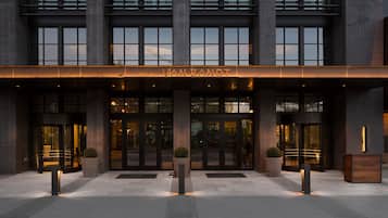 A hotel entrance with a modern facade, large glass doors, and a sign above the entrance.