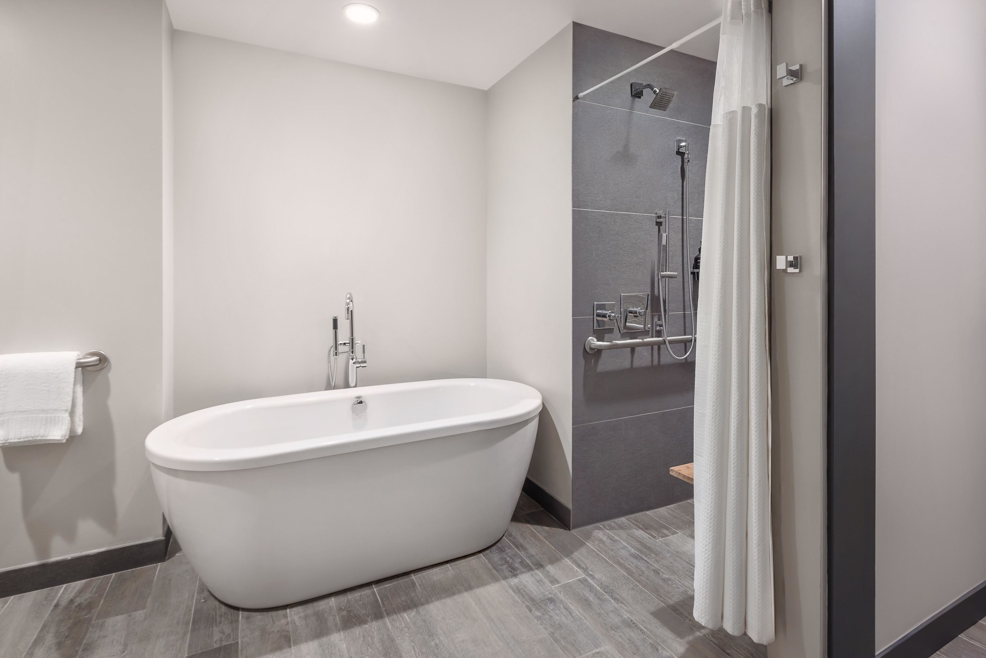 A modern bathroom with a freestanding bathtub, a shower area, and a towel rack.
