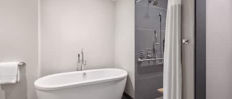 A modern bathroom with a freestanding bathtub, a shower area, and a towel rack.