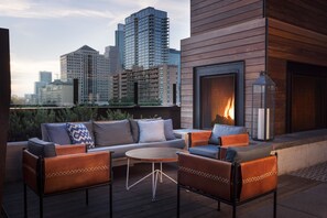 A rooftop terrace with a modern sofa set, a round table, and a fireplace. - Hotel Van Zandt (Austin)