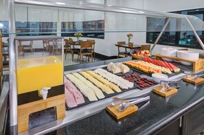 A buffet with various food items and a juice dispenser. - Hotel Domani (Guarulhos)