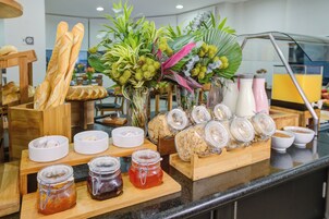 Un bufé de desayuno con pan, bollería y diferentes salsas.