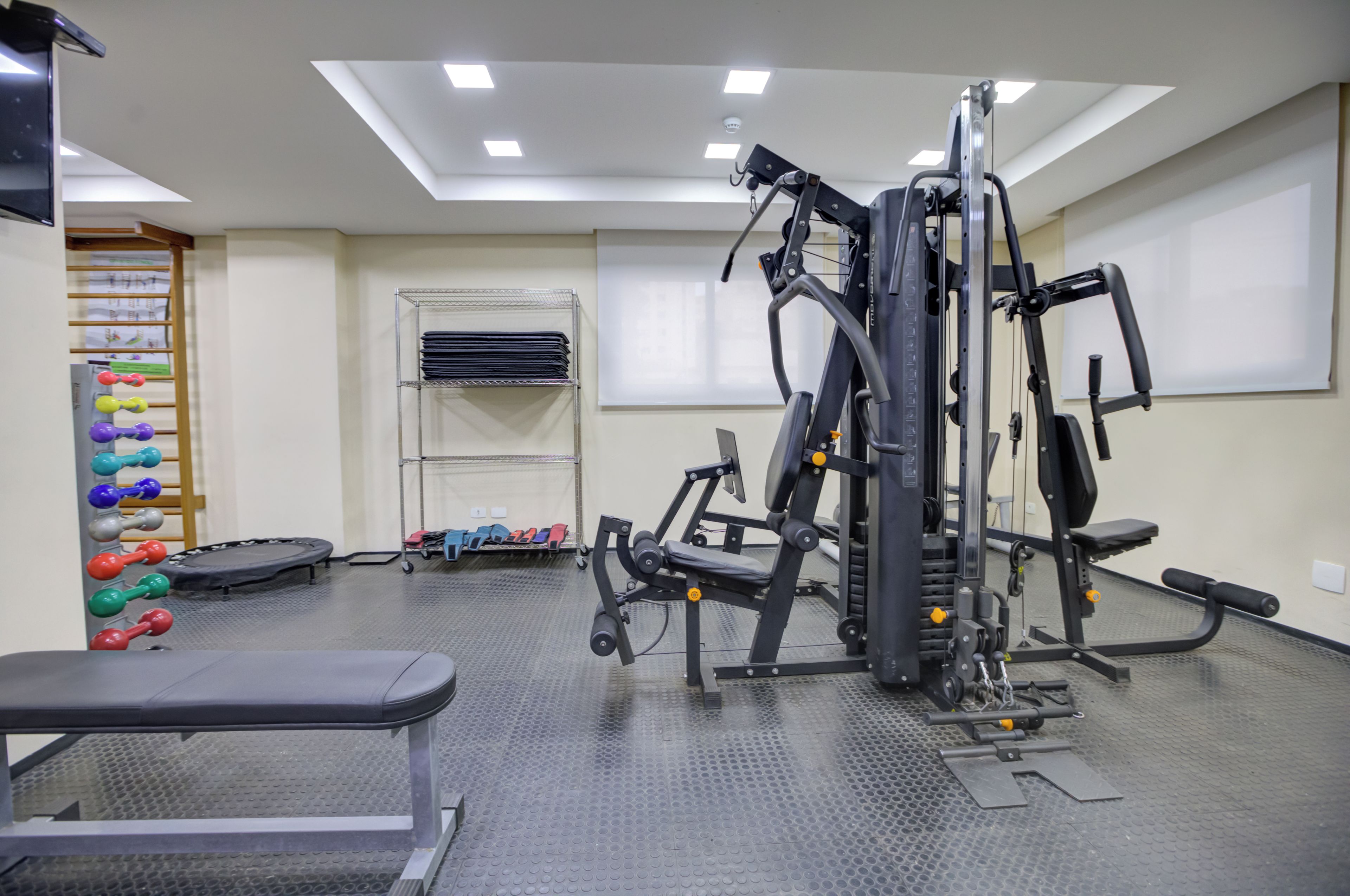 Een sportschool met trainingsapparatuur, een bank en een dumbbellsrek.
