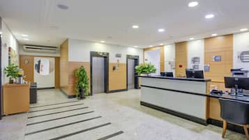 A reception area with a reception desk, two elevators, and a potted plant.