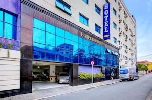 A hotel with a large glass facade, a sign reading 'HOTEL DOMANI', and a van parked outside. - Hotel Domani (Guarulhos)
