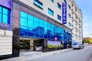 Un hotel con un amplio ventanal de vidrio, un cartel que dice 'HOTEL DOMANI' y una camioneta estacionada afuera.