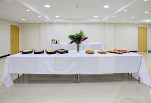 Una mesa de buffet con diferentes alimentos y salsas en una habitación bien iluminada, con piso de baldosas y paredes lisas.