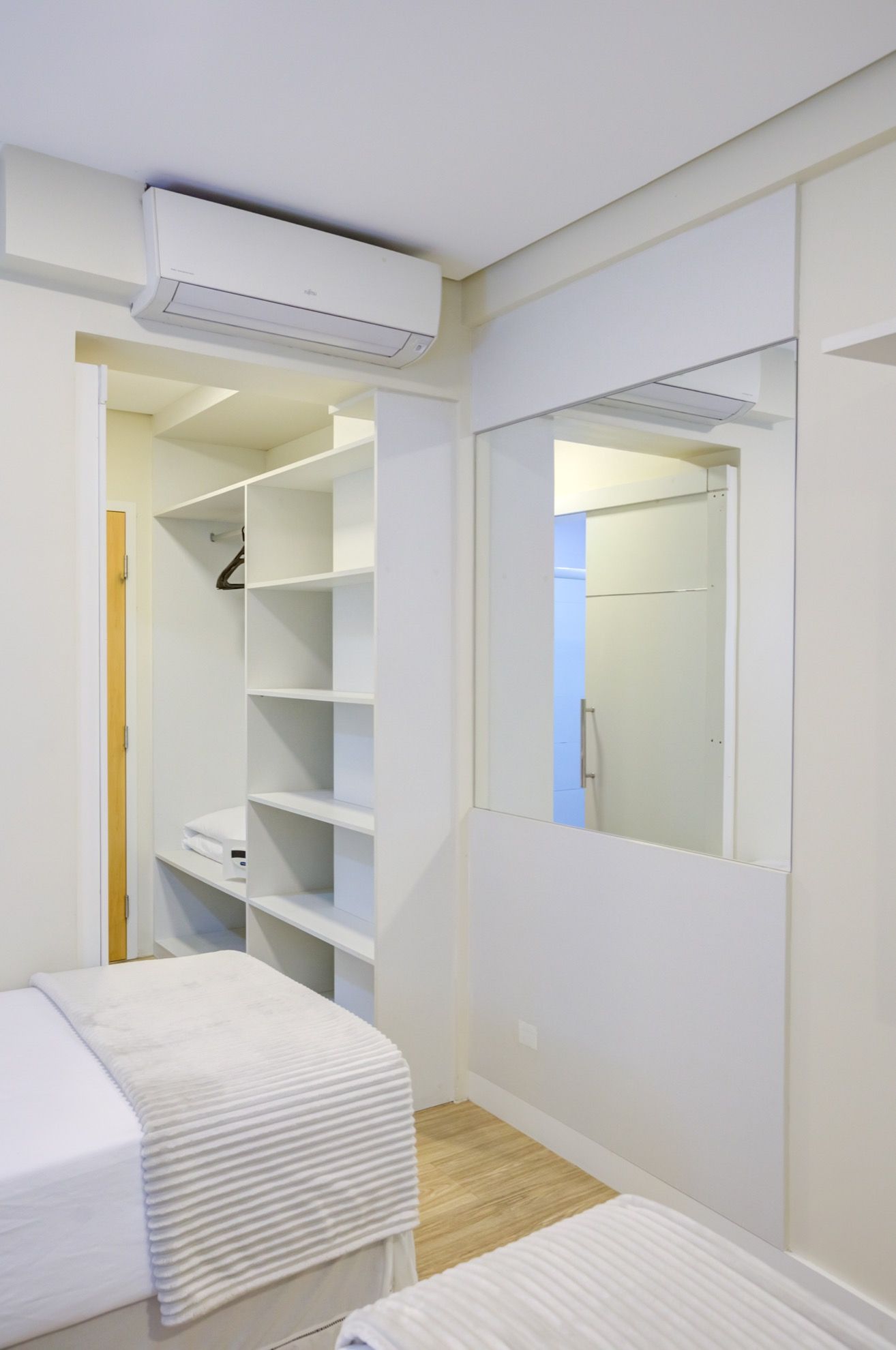 Un dormitorio con cama, vestidor y armario con espejo.