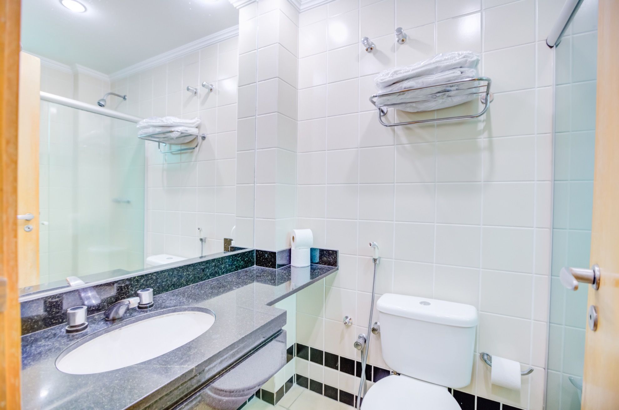 Un baño moderno con lavamanos de mármol, cabina de ducha de vidrio y retrete.