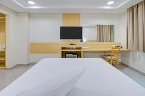A hotel room with a bed, a desk, a chair, a television, and a window with curtains. - Hotel Domani (Guarulhos)