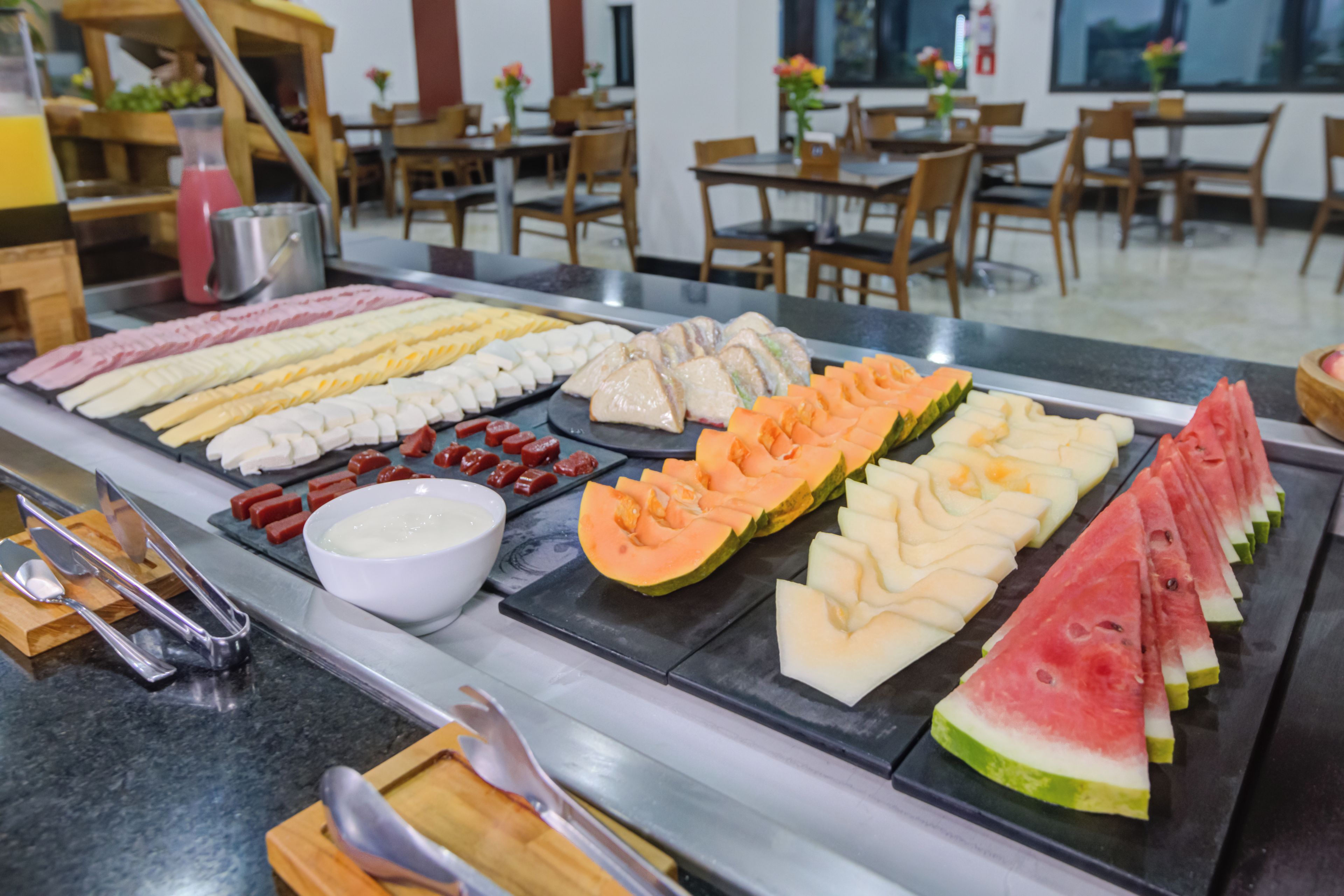 Een buffet met diverse gerechten, waaronder vleeswaren, kazen en fruit.