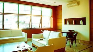 A modern hotel room with a large window, a white sofa, a small table, and a chair. - Hotel Domani (Guarulhos)