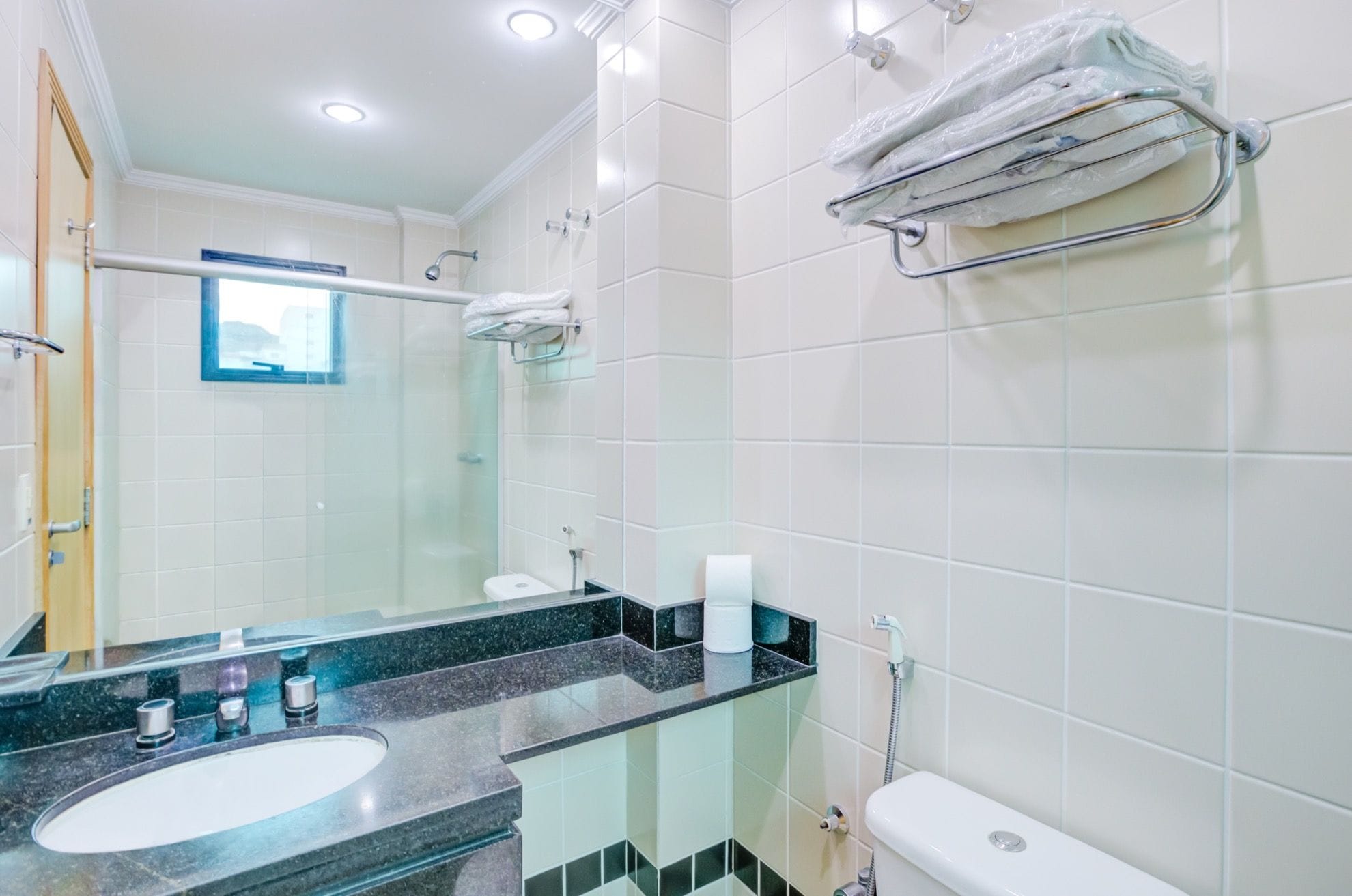 Un baño moderno con cabina de ducha de vidrio, un lavamanos con encimera negra y un inodoro.