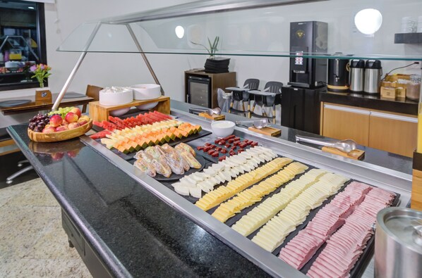 A buffet with various food items including fruits, vegetables, and prepared dishes. - Hotel Domani (Guarulhos)
