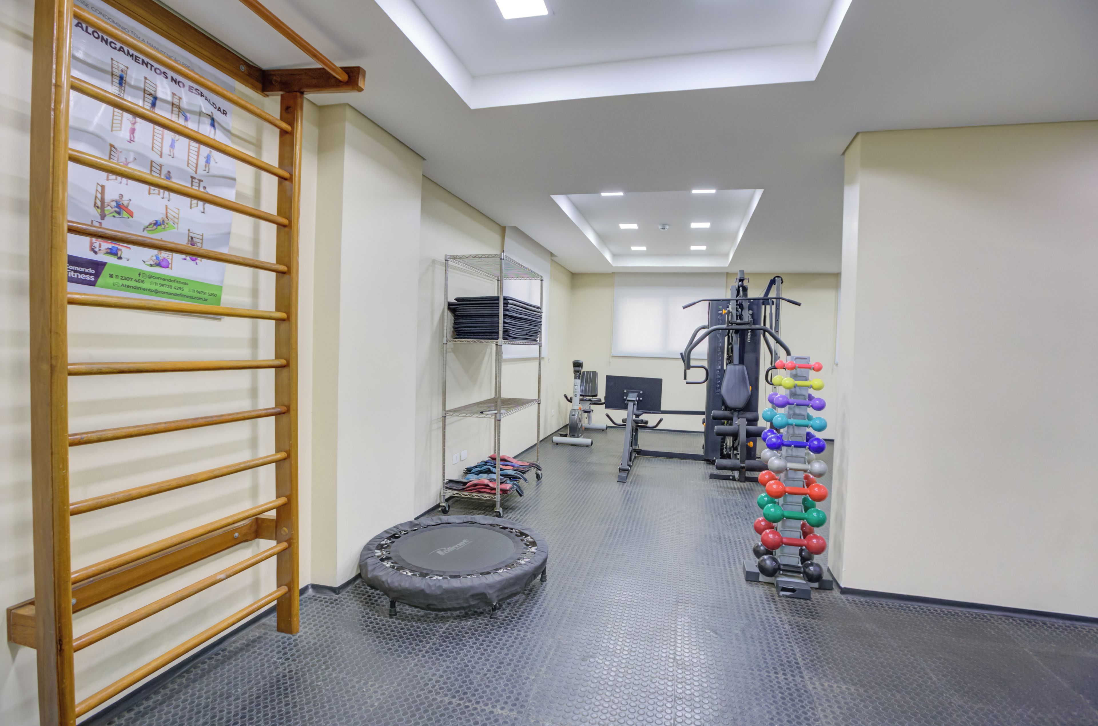A gym with exercise equipment, a trampoline, and a wall-mounted rack.